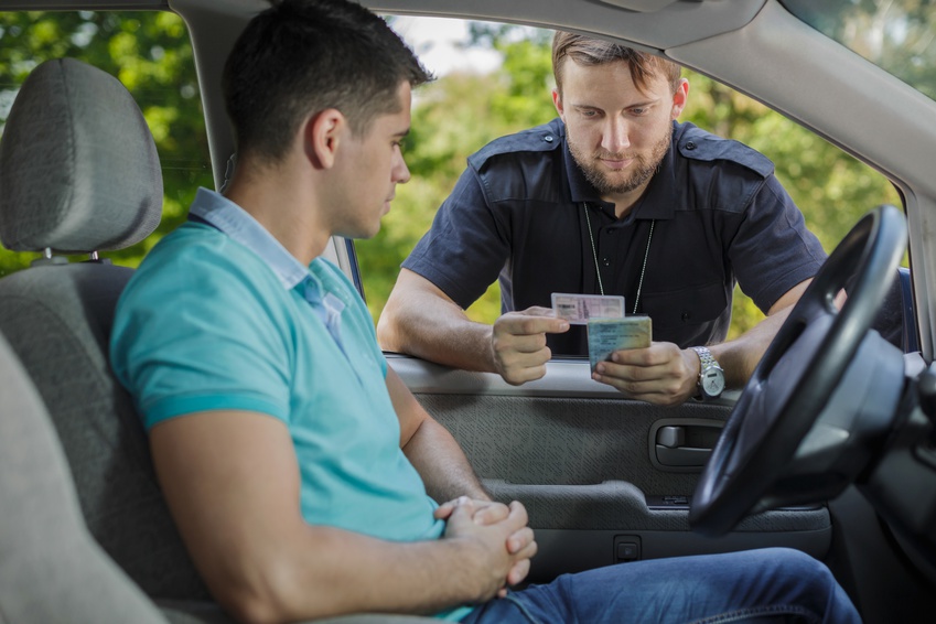 Experienced policeman is checking young man's driving licence